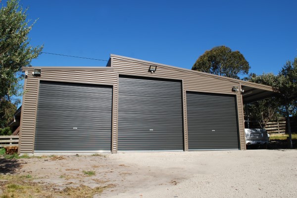 A triple car skillion roof garage with a lean to and an additional 4th open bay to the right