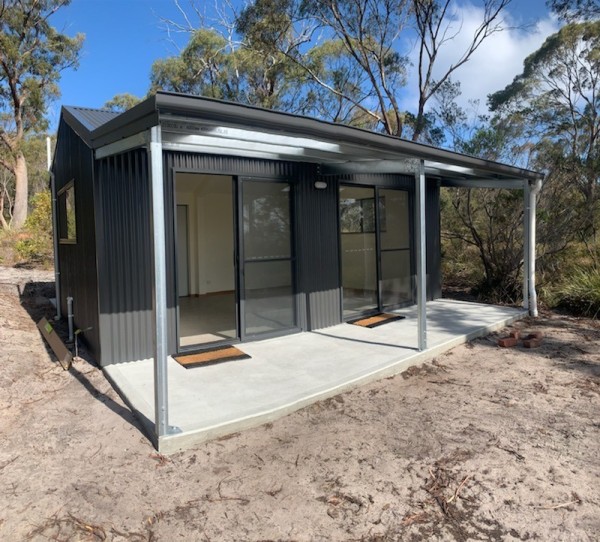 A shed converted into a workshop with a concrete verandah set among gum trees