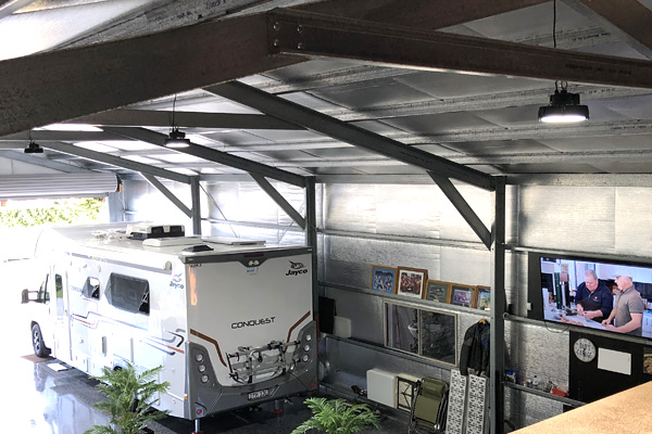 Interior shot of large residential shed looking down from mezzanine floor with a white RV parked