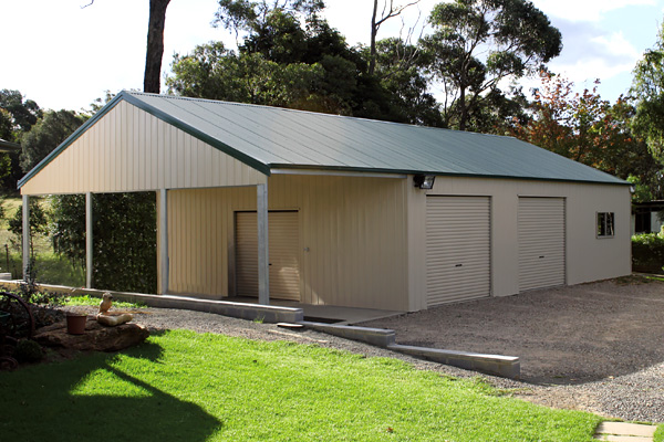 Cream shed with green roof with garaport, single roller door on front and two side roller doors