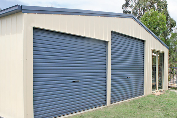 Gable roof cream shed with two blue roller doors and blue trim plus glass sliding door